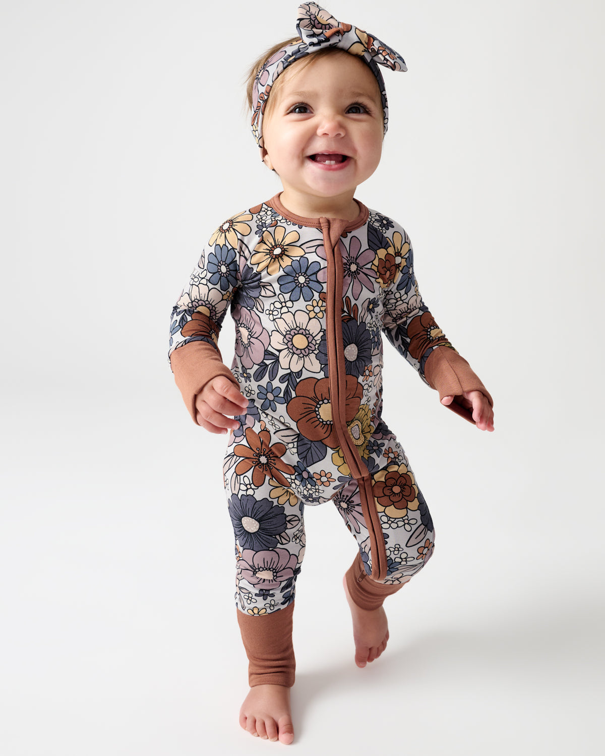 Walking baby wearing the Wildwood Floral Zippy and Luxe Bow