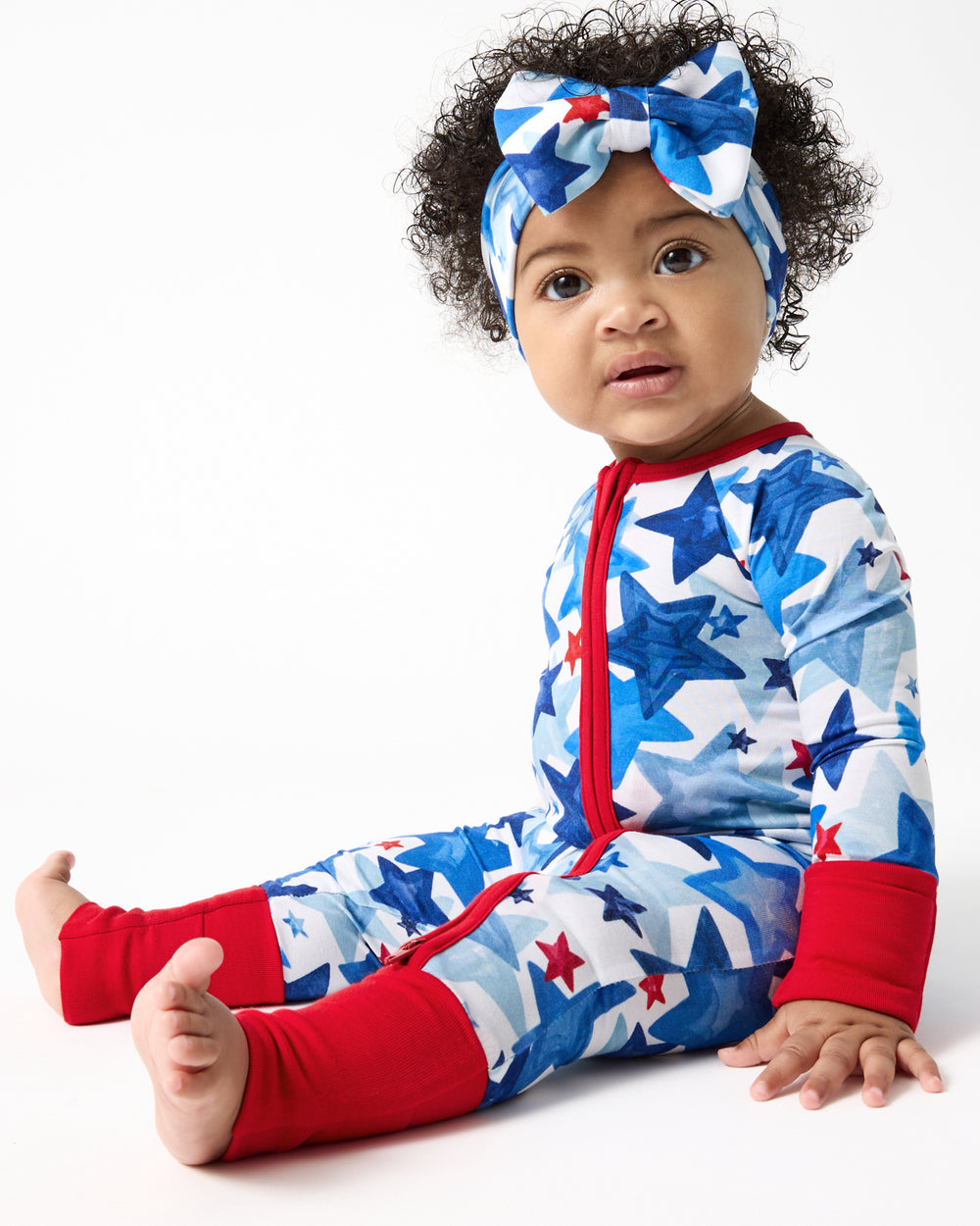 Sitting baby wearing the Starry Splash Zippy and Luxe Bow Headband
