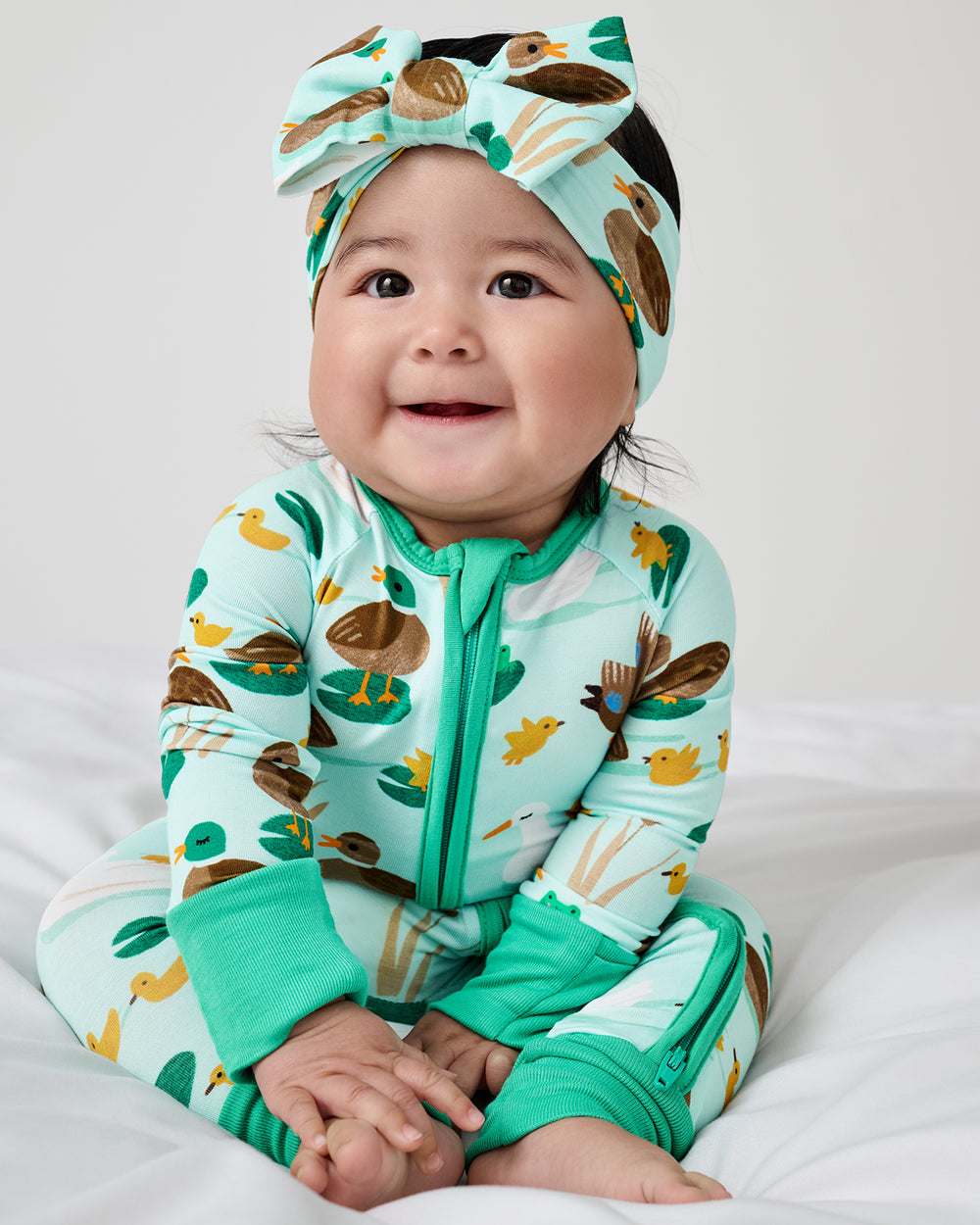 Sitting newborn wearing the Puddle Jumpers Luxe Bow Headband and Zippy
