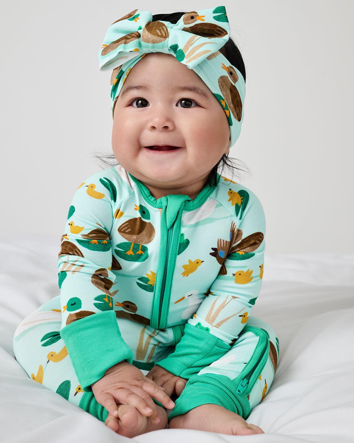 Sitting newborn wearing the Puddle Jumpers Luxe Bow Headband and Zippy