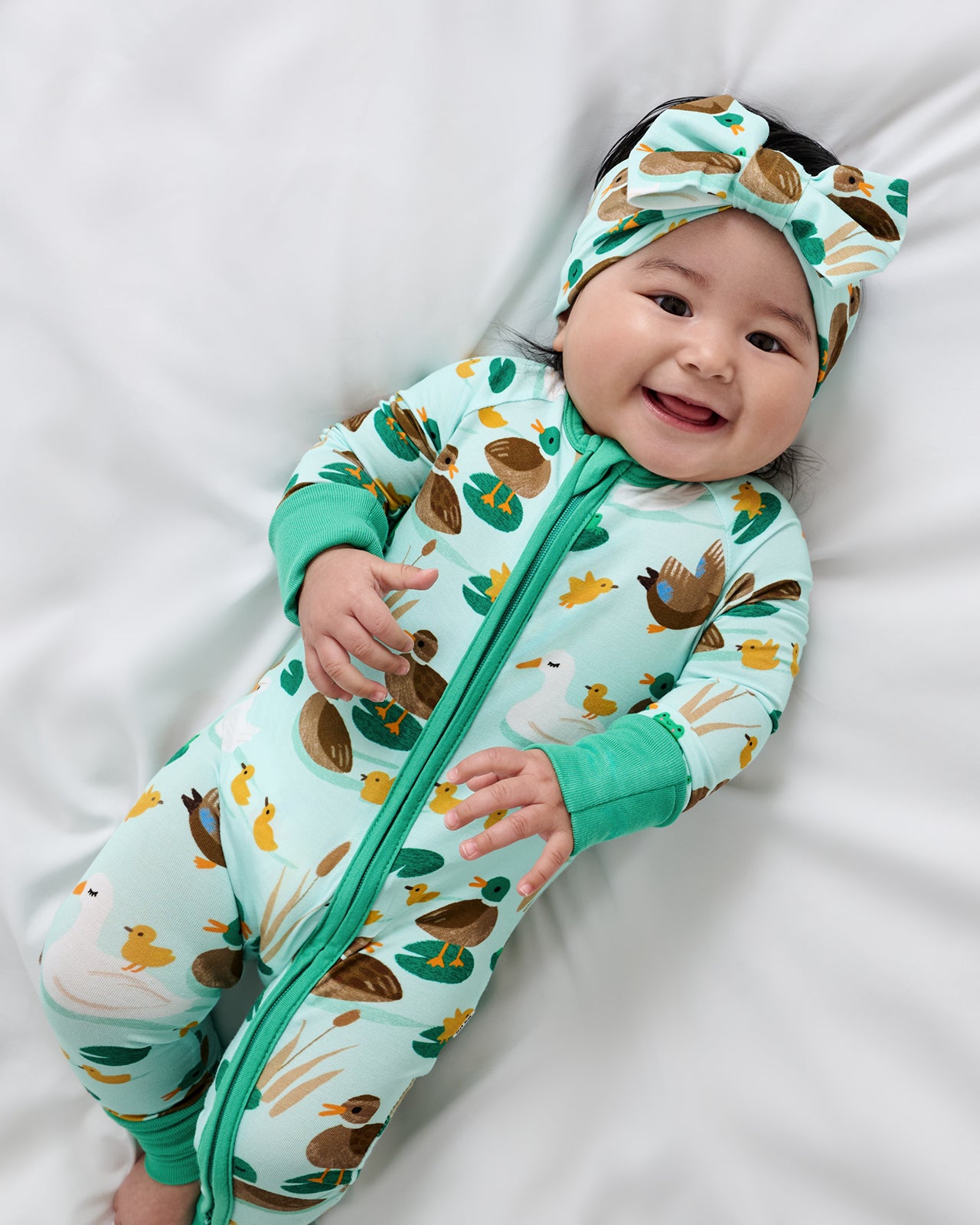 Aerial view of baby wearing the Puddle Jumpers Luxe Bow Headband and Zippy