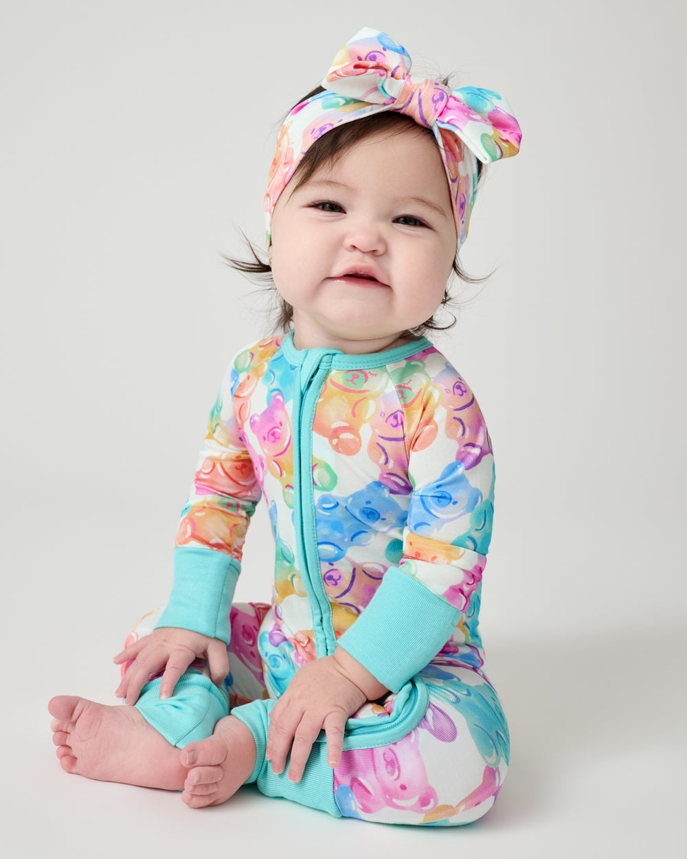 Sitting baby wearing the Gummy Giggles Luxe Bow Headband and Zippy