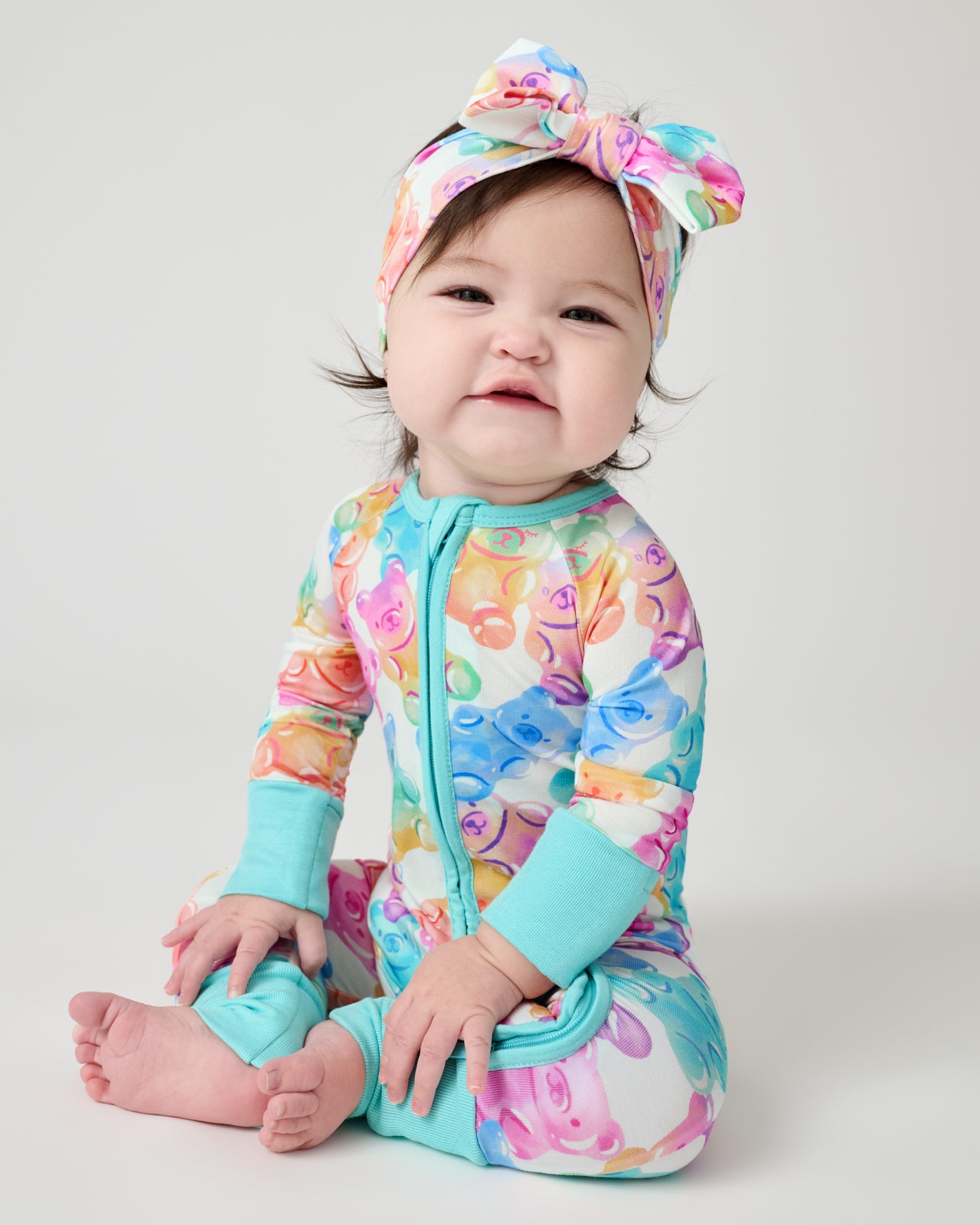 Sitting baby wearing the Gummy Giggles Luxe Bow Headband and Zippy