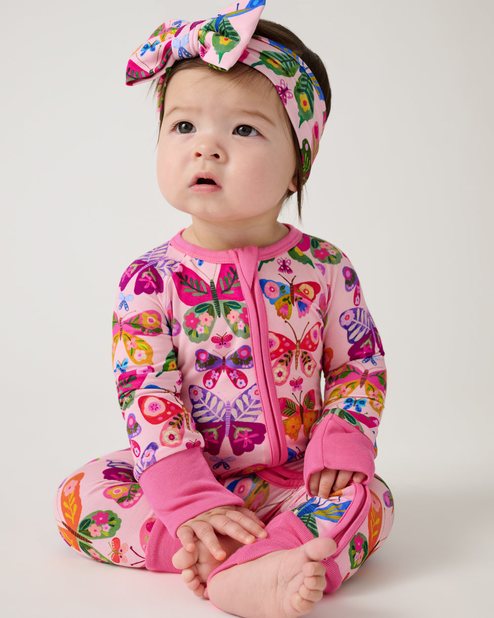 Sitting baby wearing the Flutter Garden Luxe Bow Headband and Headband