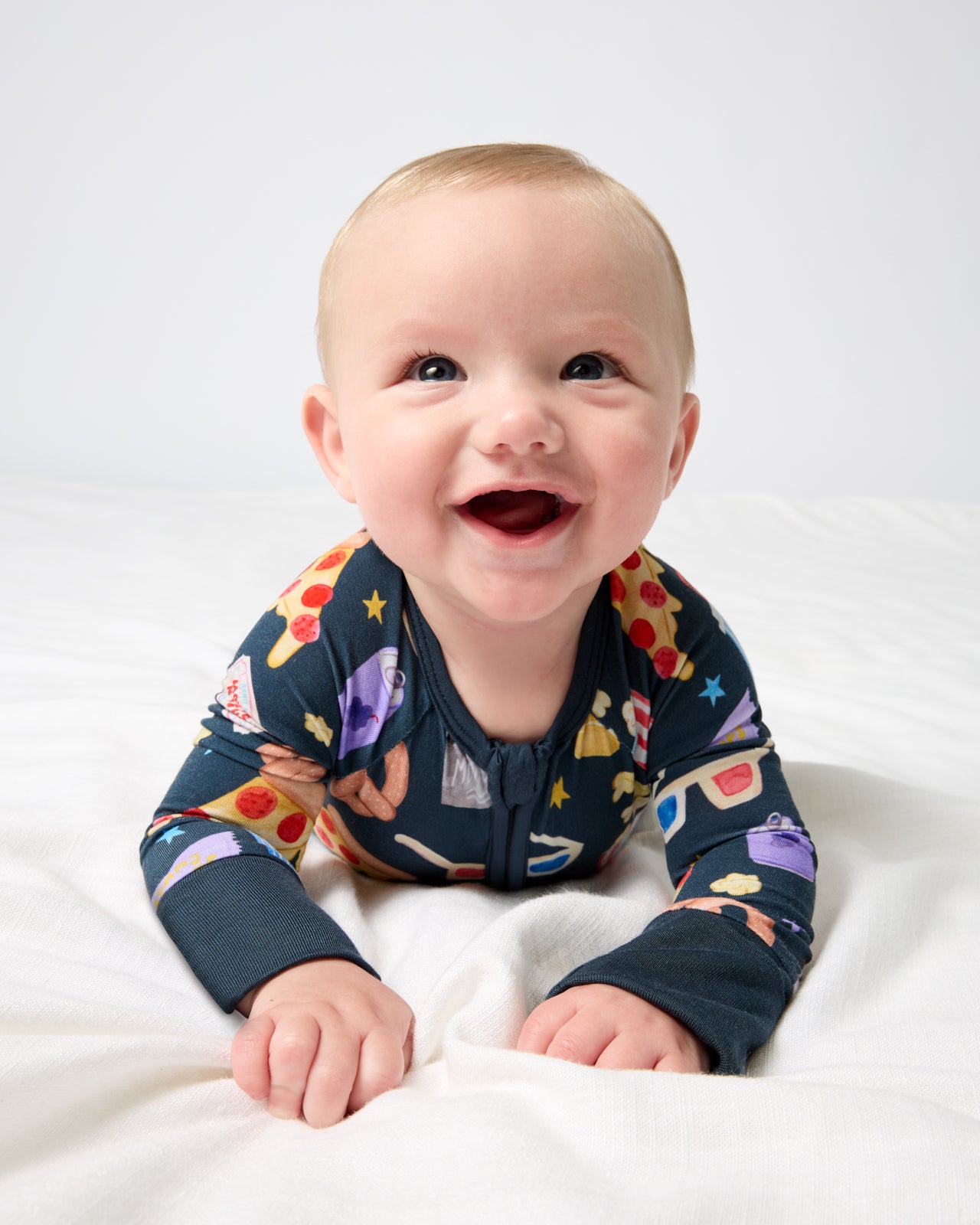Baby on his tummy wearing the Movie Marathon Zippy