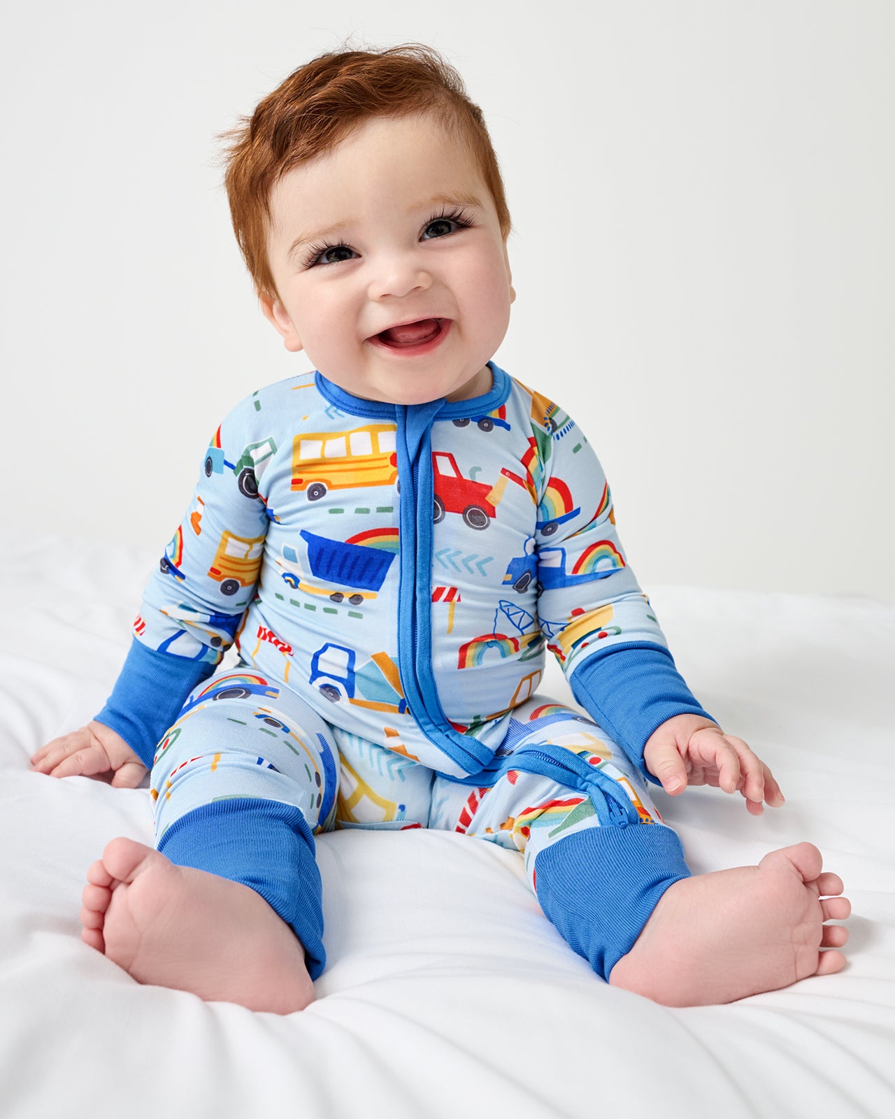 Sitting baby wearing the Rainbow Trucks Zippy