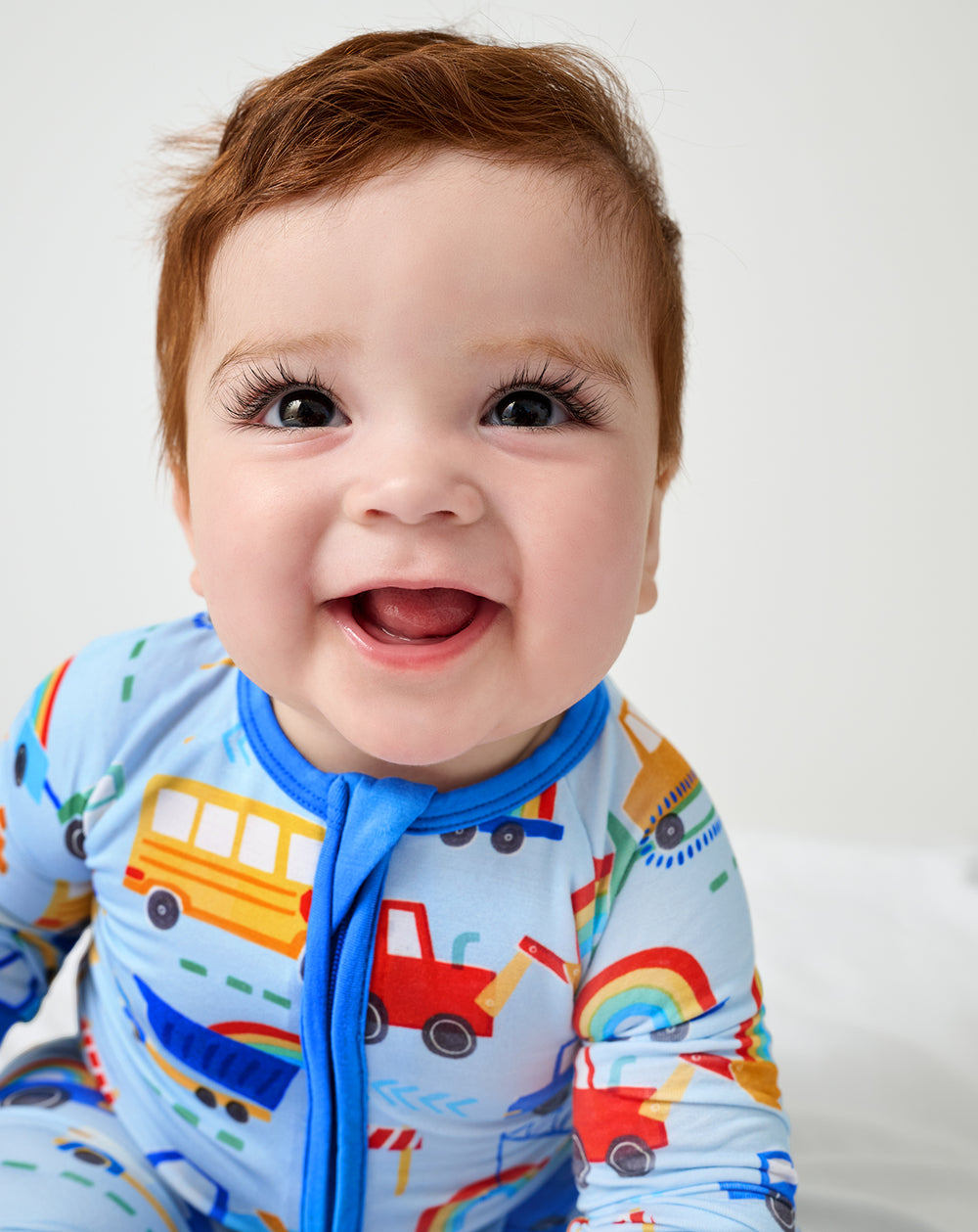 Close up of baby wearing the Rainbow Trucks Zippy