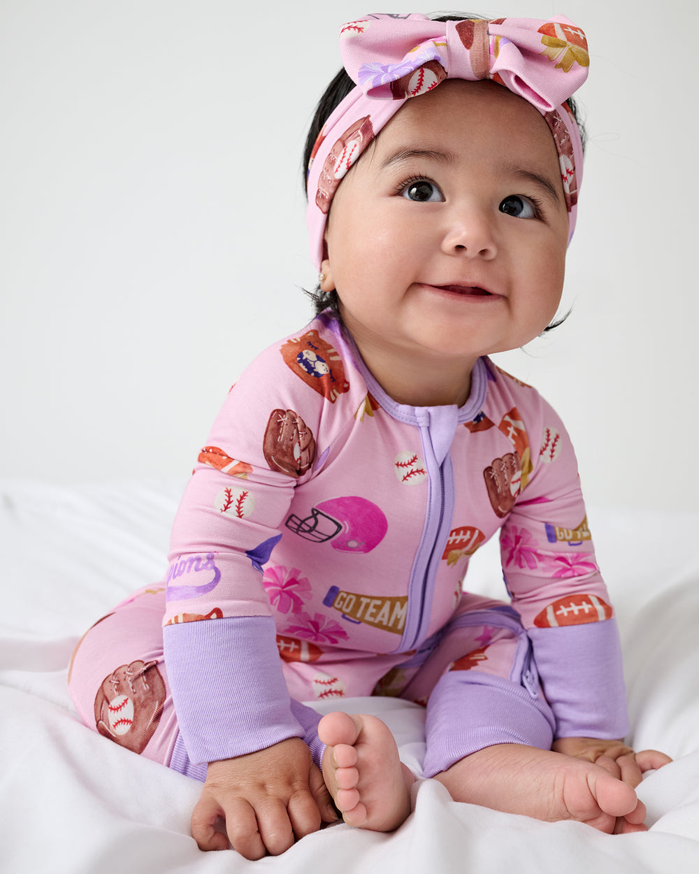 Sitting baby wearing the Team Spirit Pink Zippy and Luxe Bow Headband