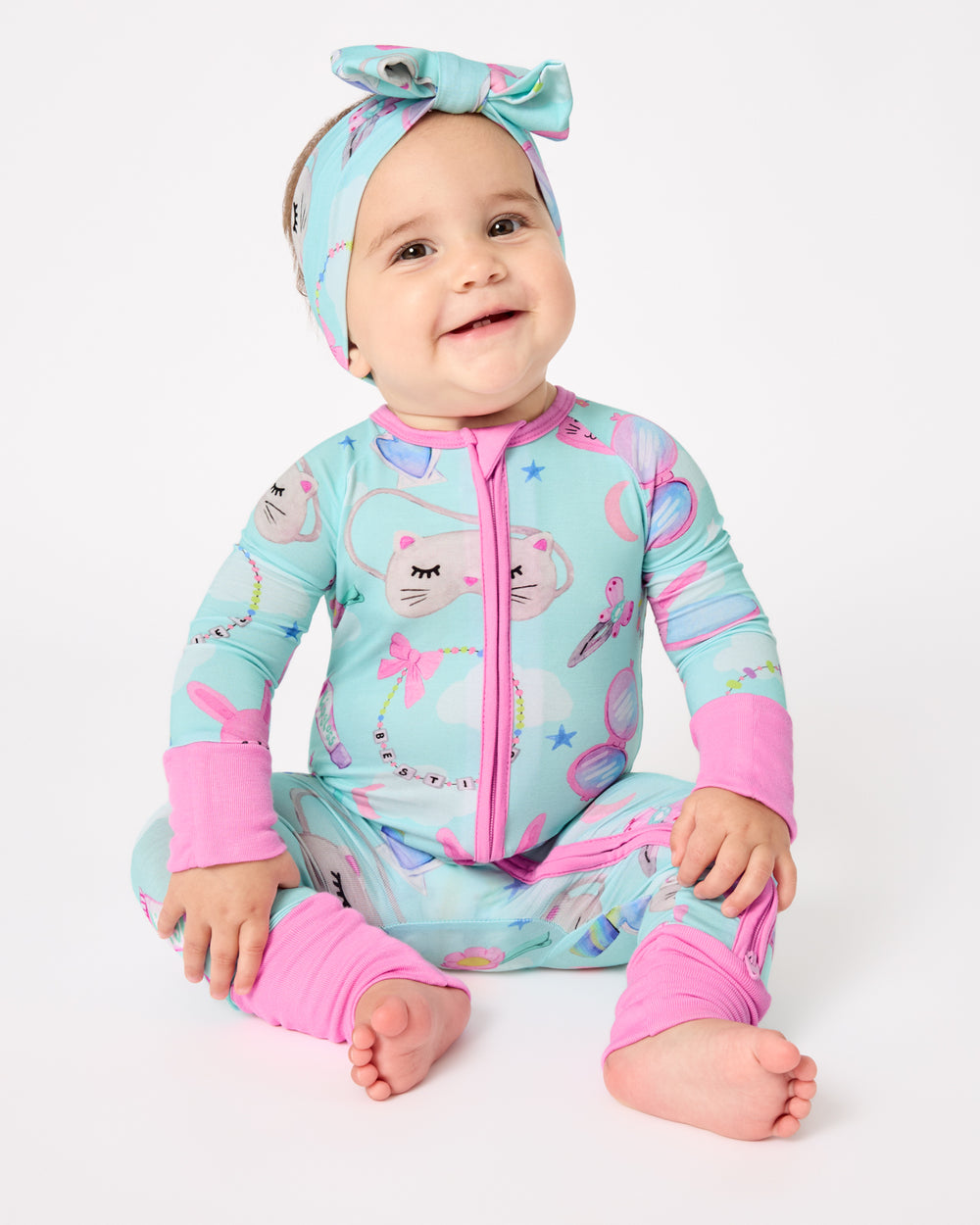 Sitting baby wearing the Slumber Club Zippy and Luxe Bow Headband