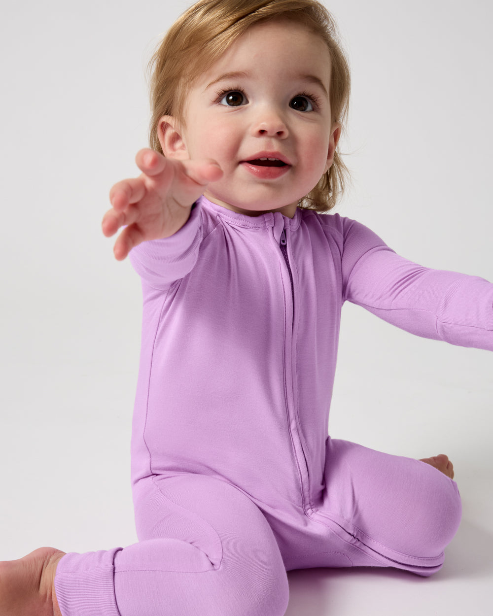 Sitting baby wearing the Soft Wisteria Zippy