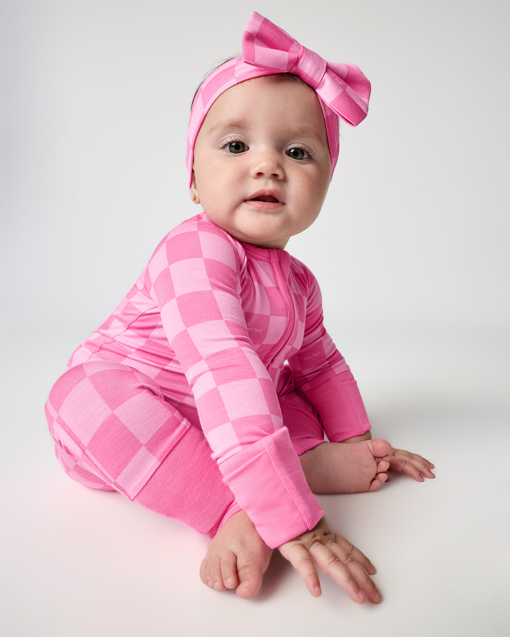 Baby wearing the Sweet Raspberry Checks Zippy with a matching luxe bow