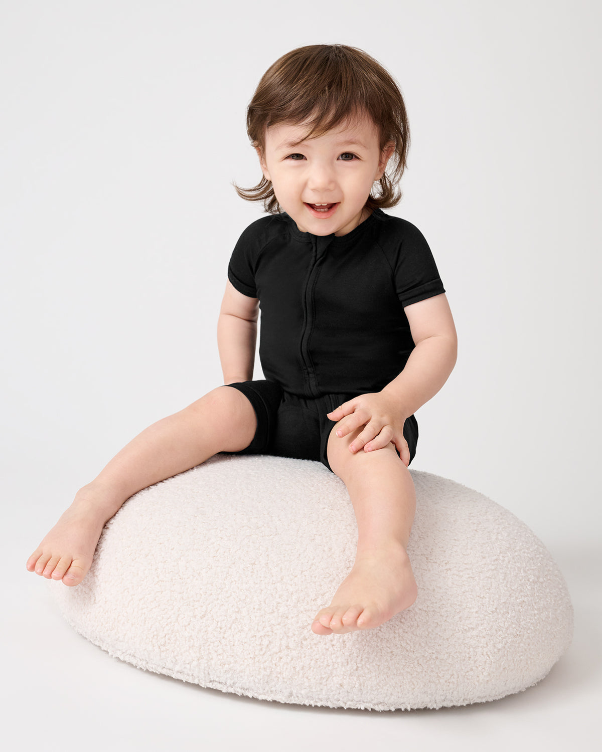 Toddler on a boucle ottoman wearing the Black Shorty Zippy