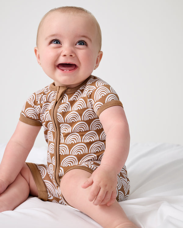 Sitting baby wearing the Rust Rainbows Shorty Zippy