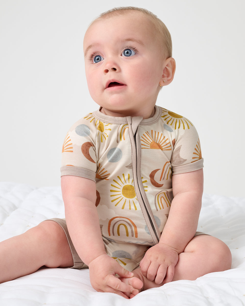 Sitting newborn wearing the Desert Sunrise Shorty Zippy