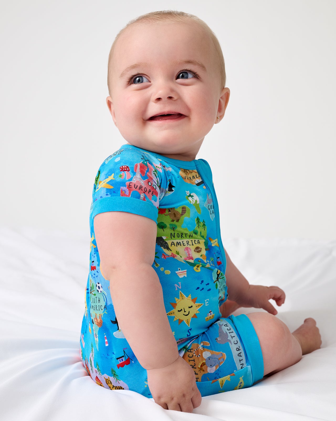 Sitting newborn wearing the Around The World Shorty Zippy