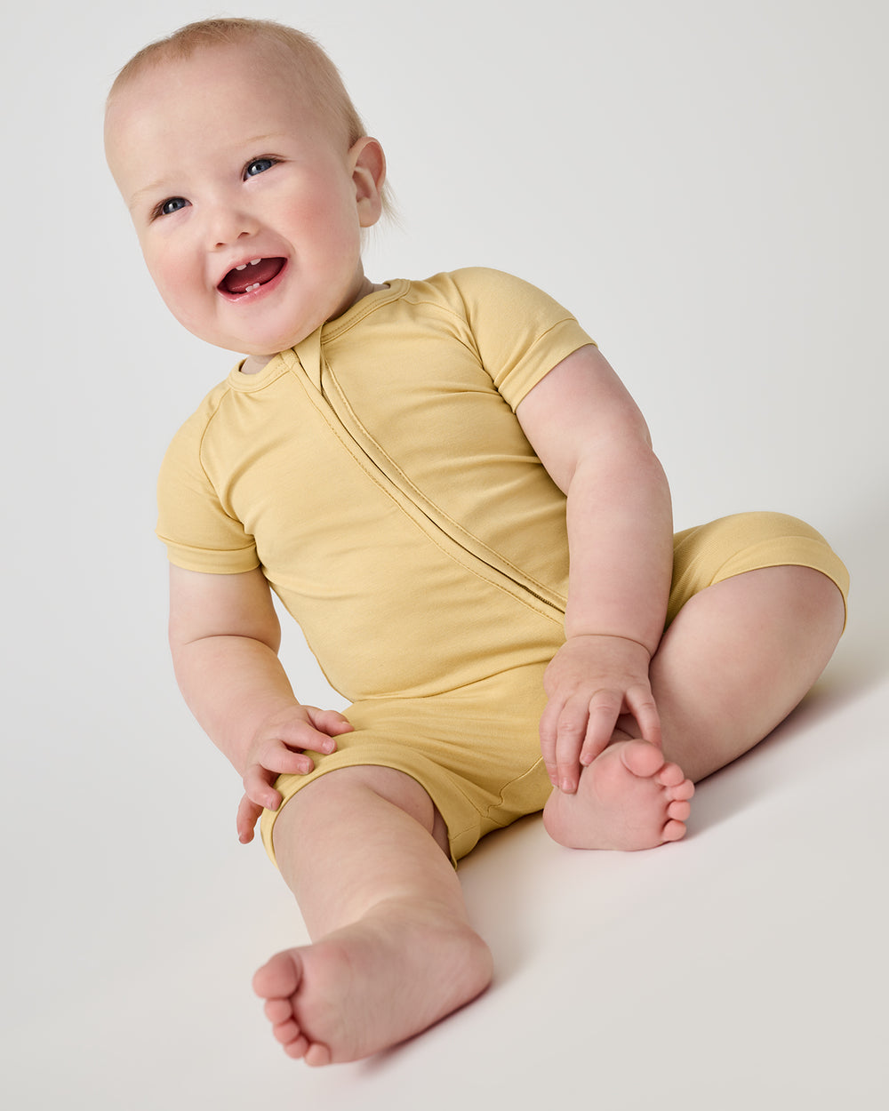 Sitting baby wearing the Sunglow Shorty Zippy