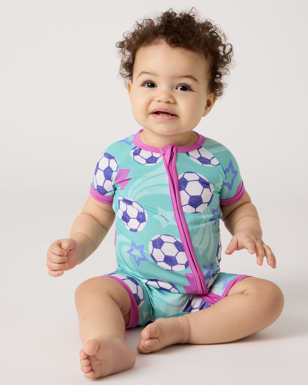 Sitting baby wearing the Aqua Soccer Stars Shorty Zippy