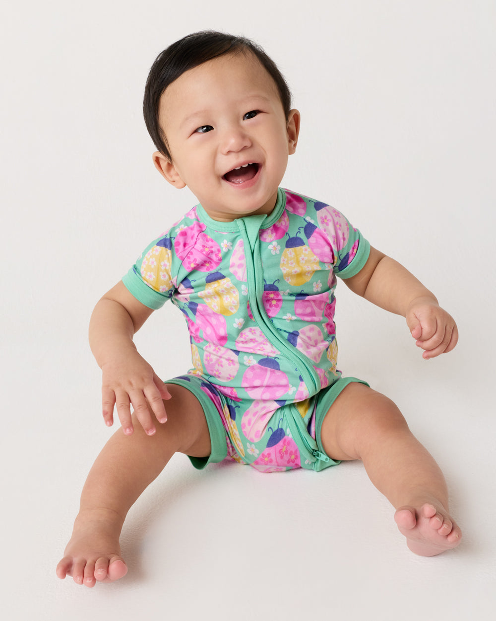 Sitting baby wearing the Ladybug Meadow Shorty Zippy