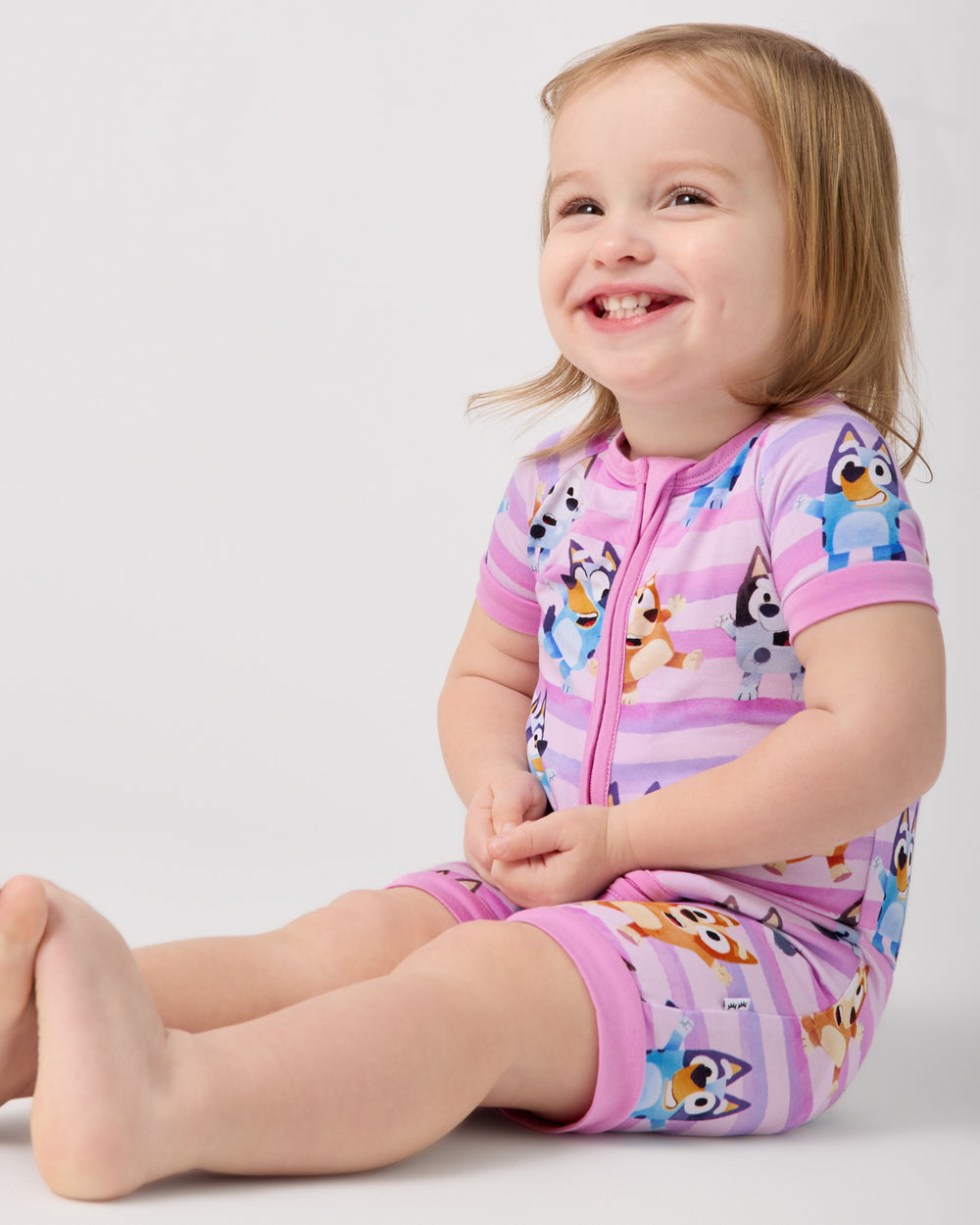 Sitting toddler wearing the Pink Bluey Dance All Day Shorty Zippy