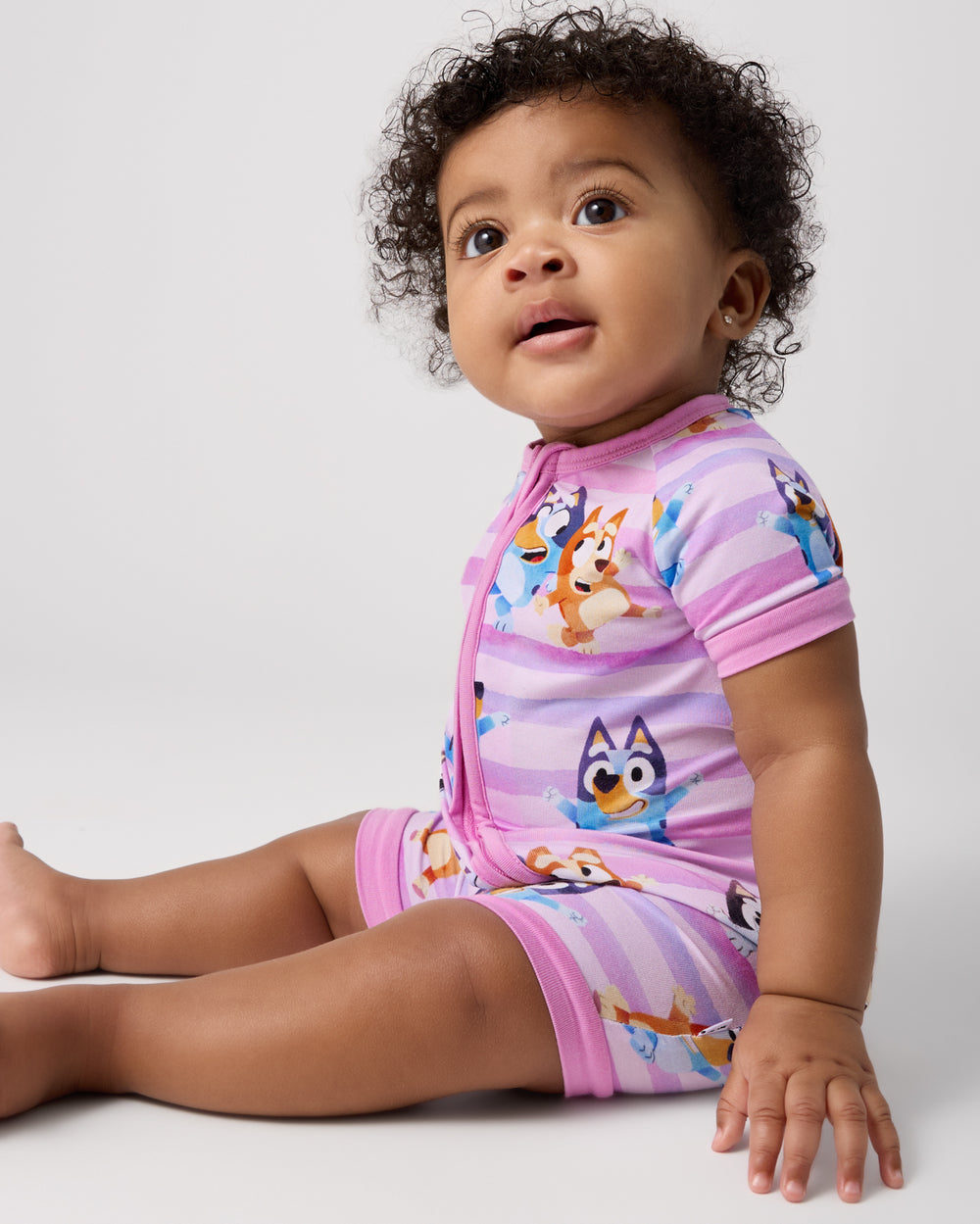 Sitting baby wearing the Pink Bluey Dance All Day Shorty Zippy