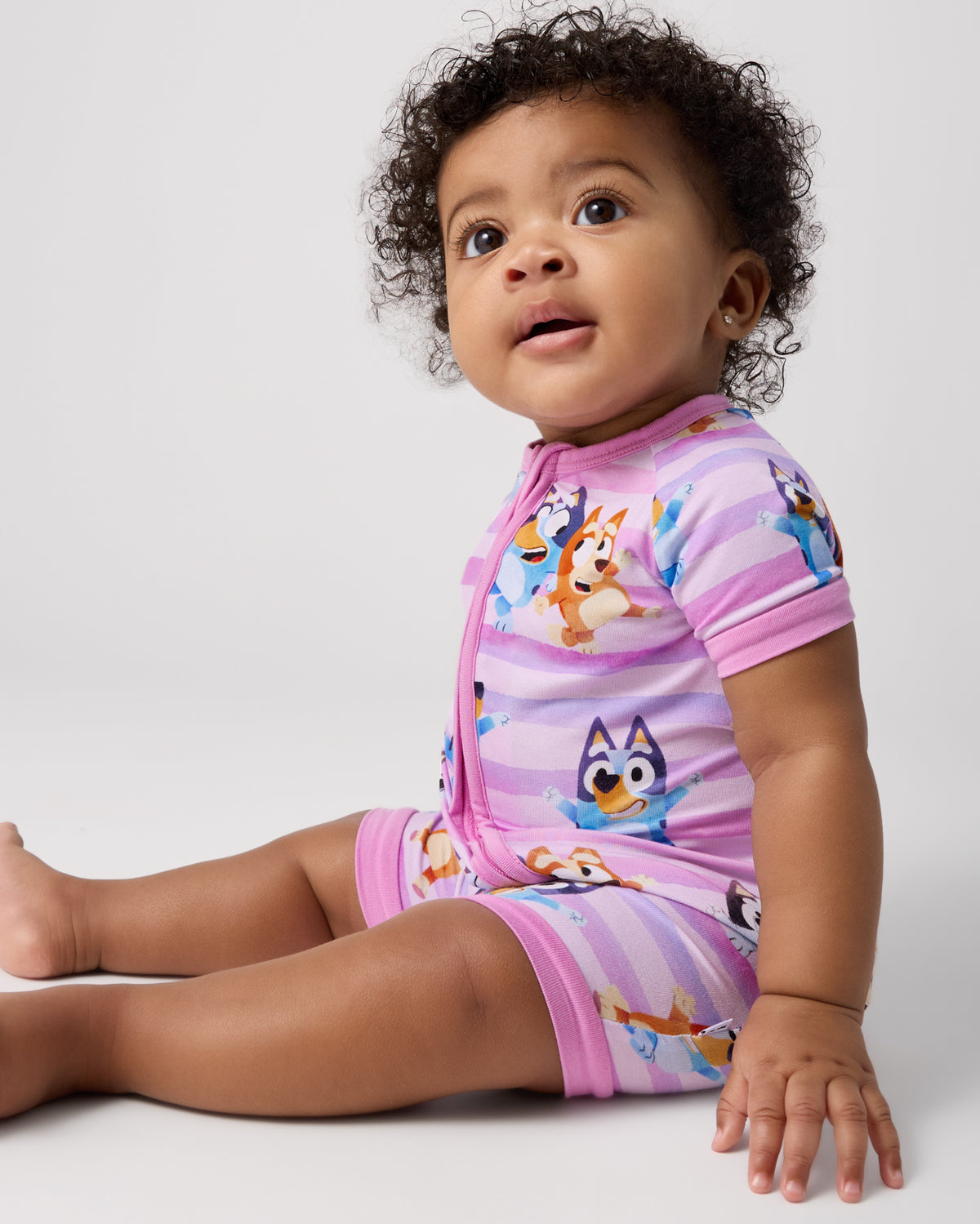 Sitting baby wearing the Pink Bluey Dance All Day Shorty Zippy