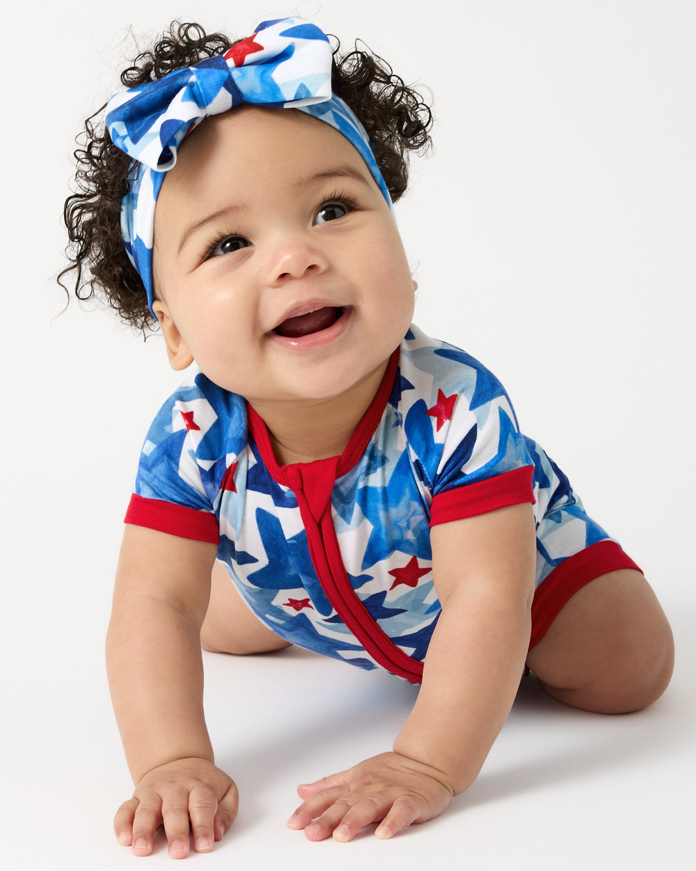 Crawling baby wearing the Starry Splash Shorty Zippy and Luxe Bow Headband