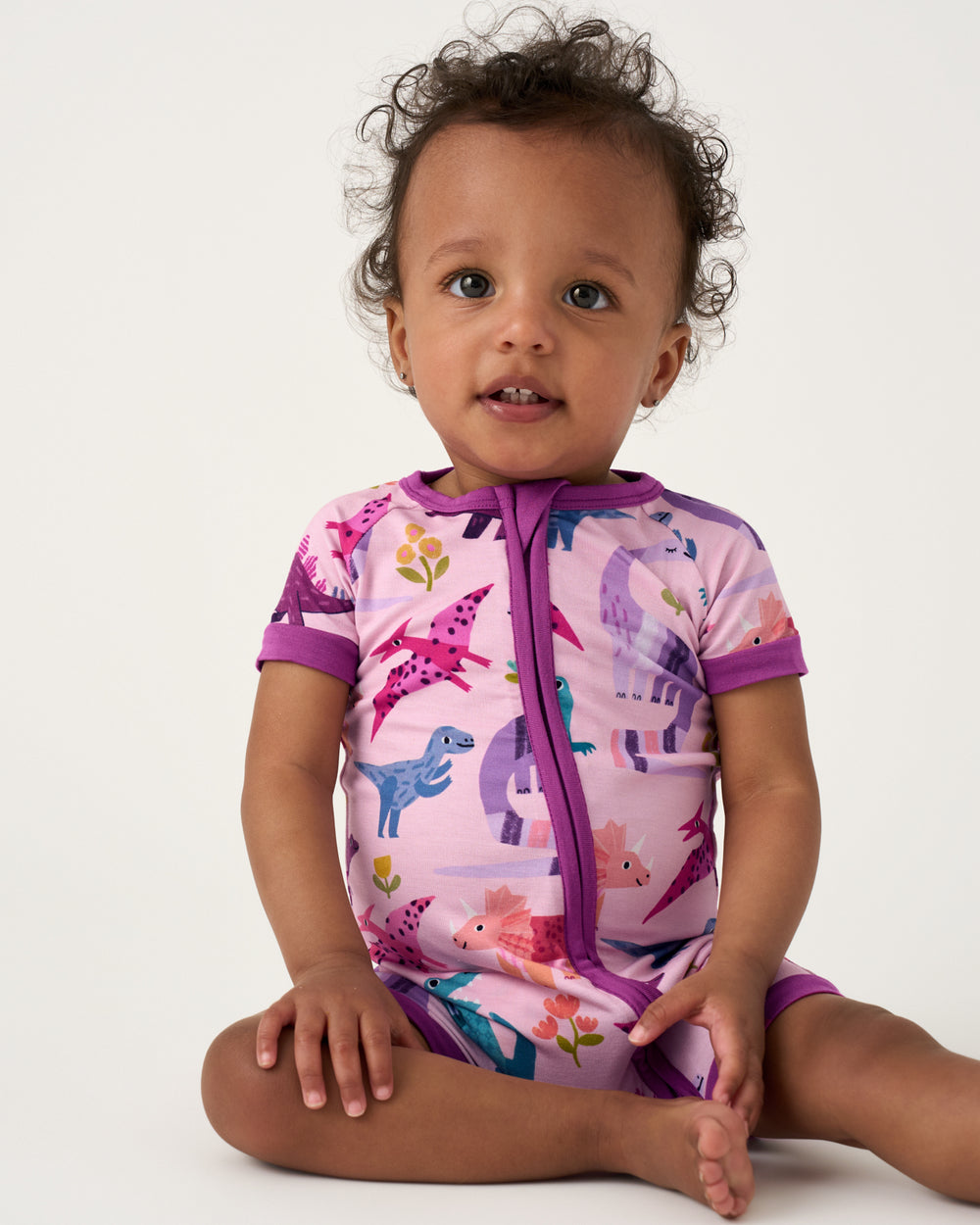 Sitting baby wearing the Pink Roar & Explore Shorty Zippy