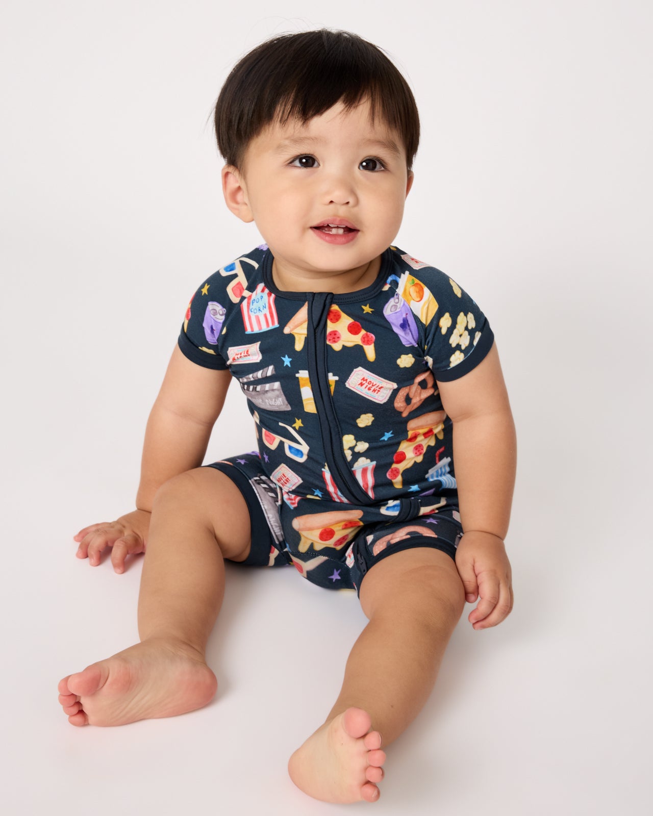 Sitting baby wearing the Movie Marathon Shorty Zippy