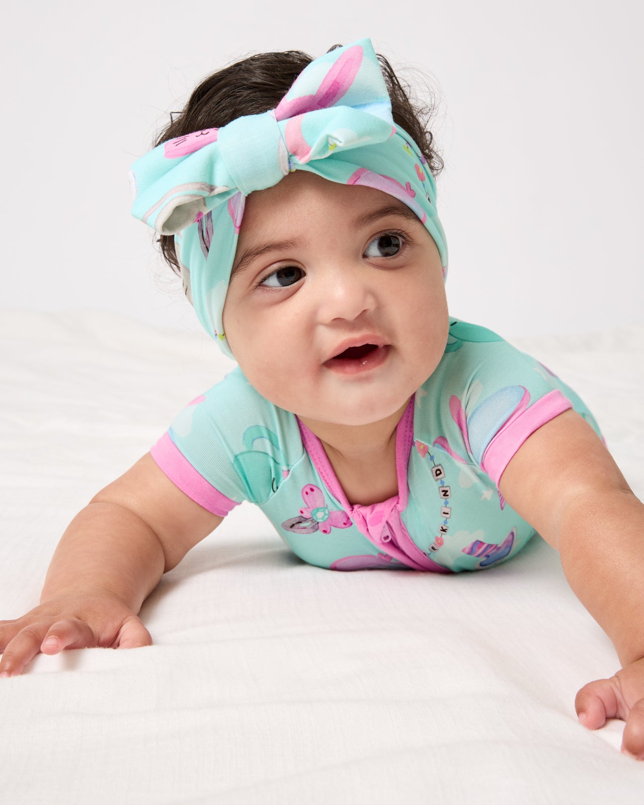 Baby on her tummy wearing the Slumber Club Luxe Bow Headband