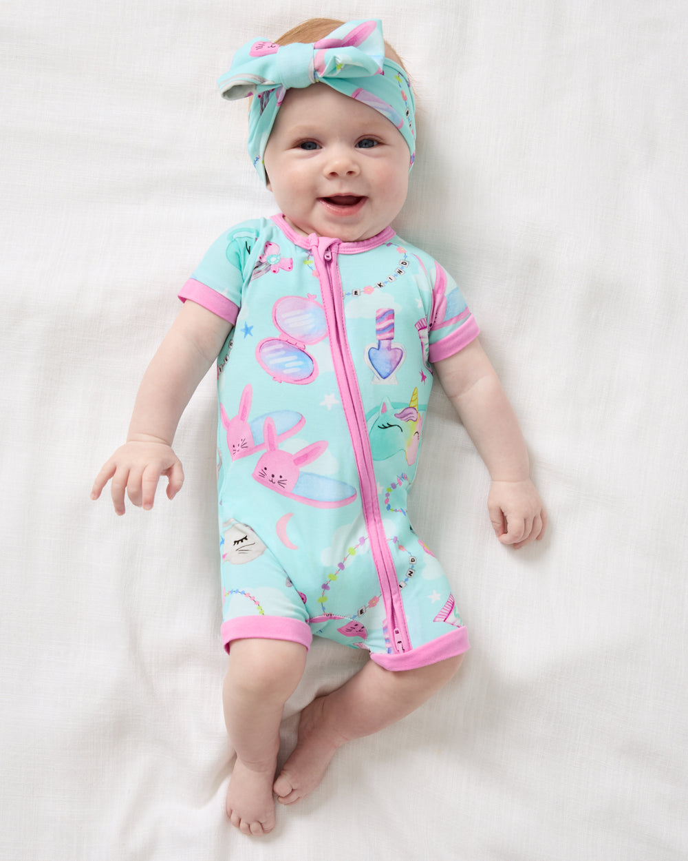 Aerial view of baby wearing the Slumber Club Luxe Bow Headband and Shorty Zippy