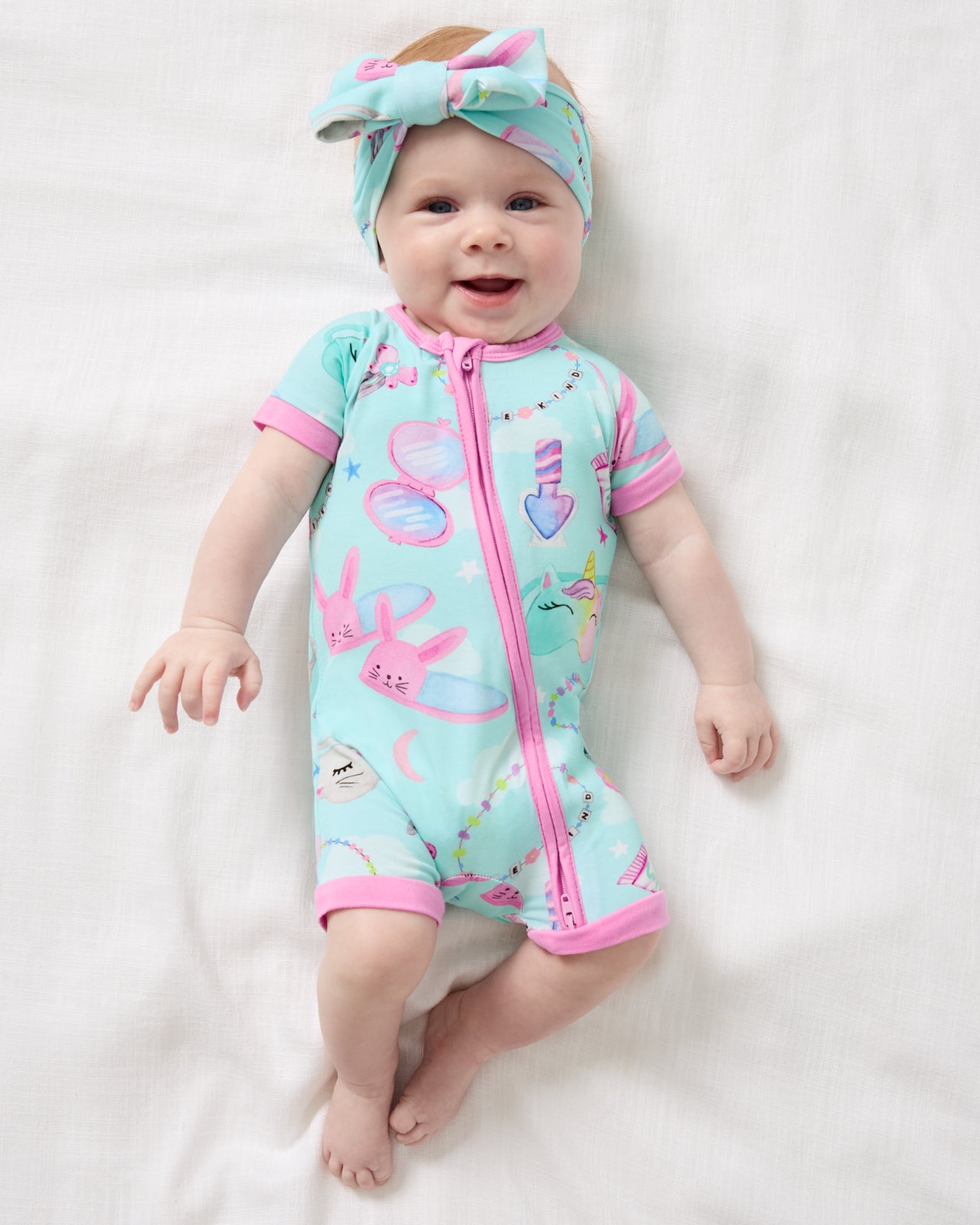 Aerial view of baby wearing the Slumber Club Luxe Bow Headband and Shorty Zippy