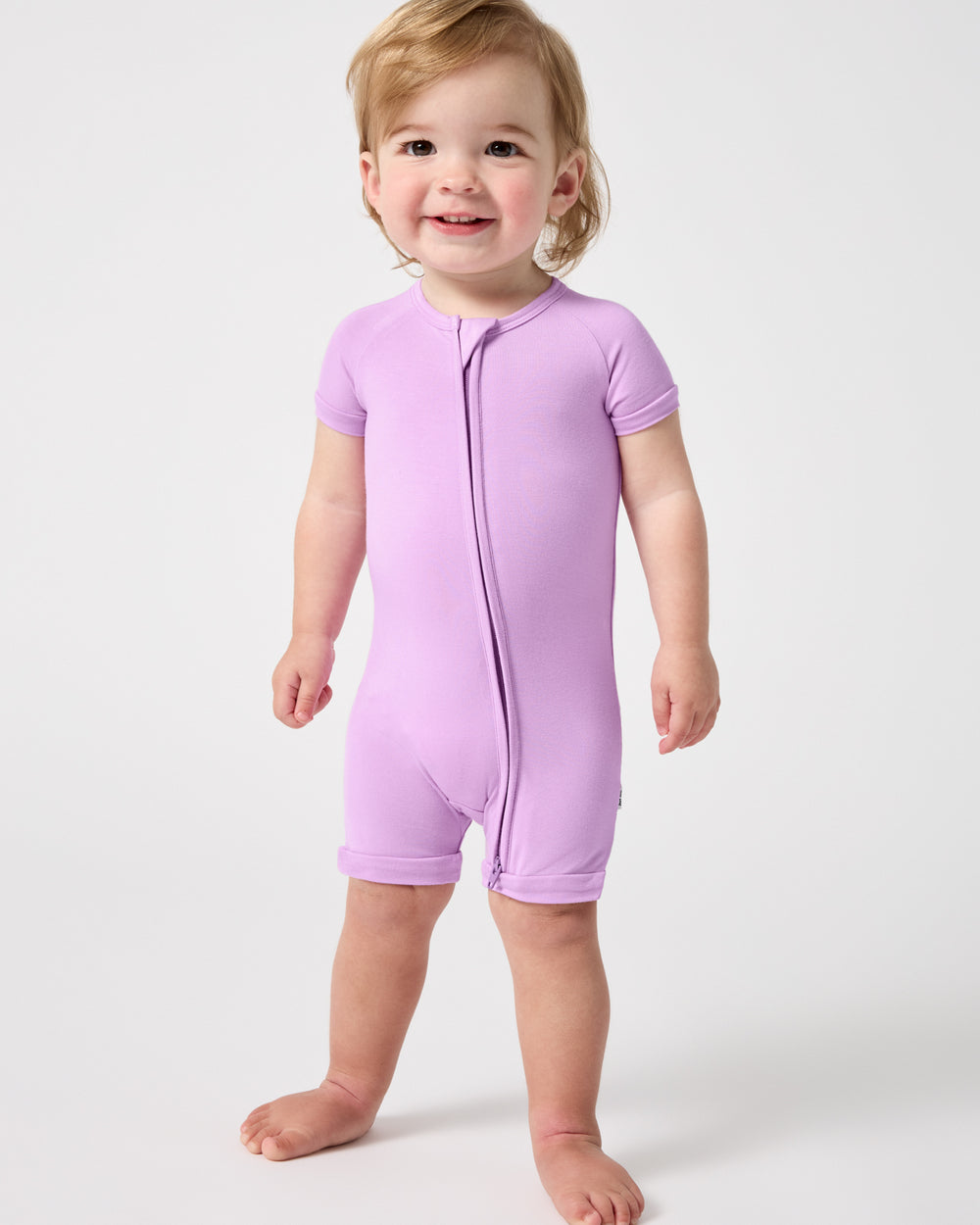 Standing baby wearing the Soft Wisteria Shorty Zippy