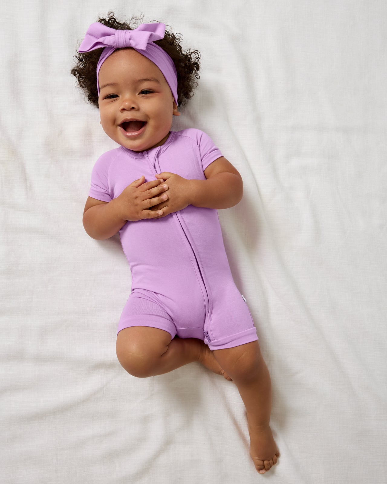 Aerial view of baby wearing the Soft Wisteria Shorty Zippy and Luxe Bow