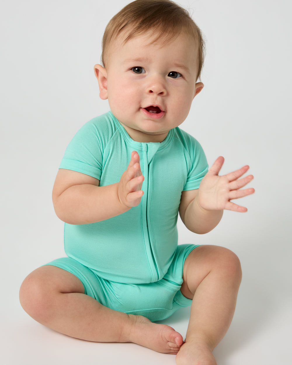Sitting baby wearing the Ocean Mist Shorty Zippy