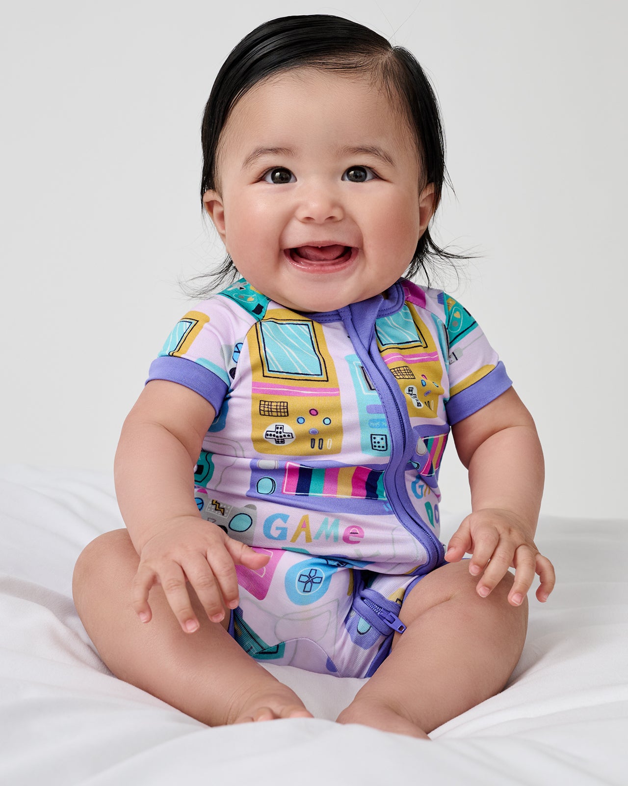 Sitting newborn wearing the Purple Game On Shorty Zippy
