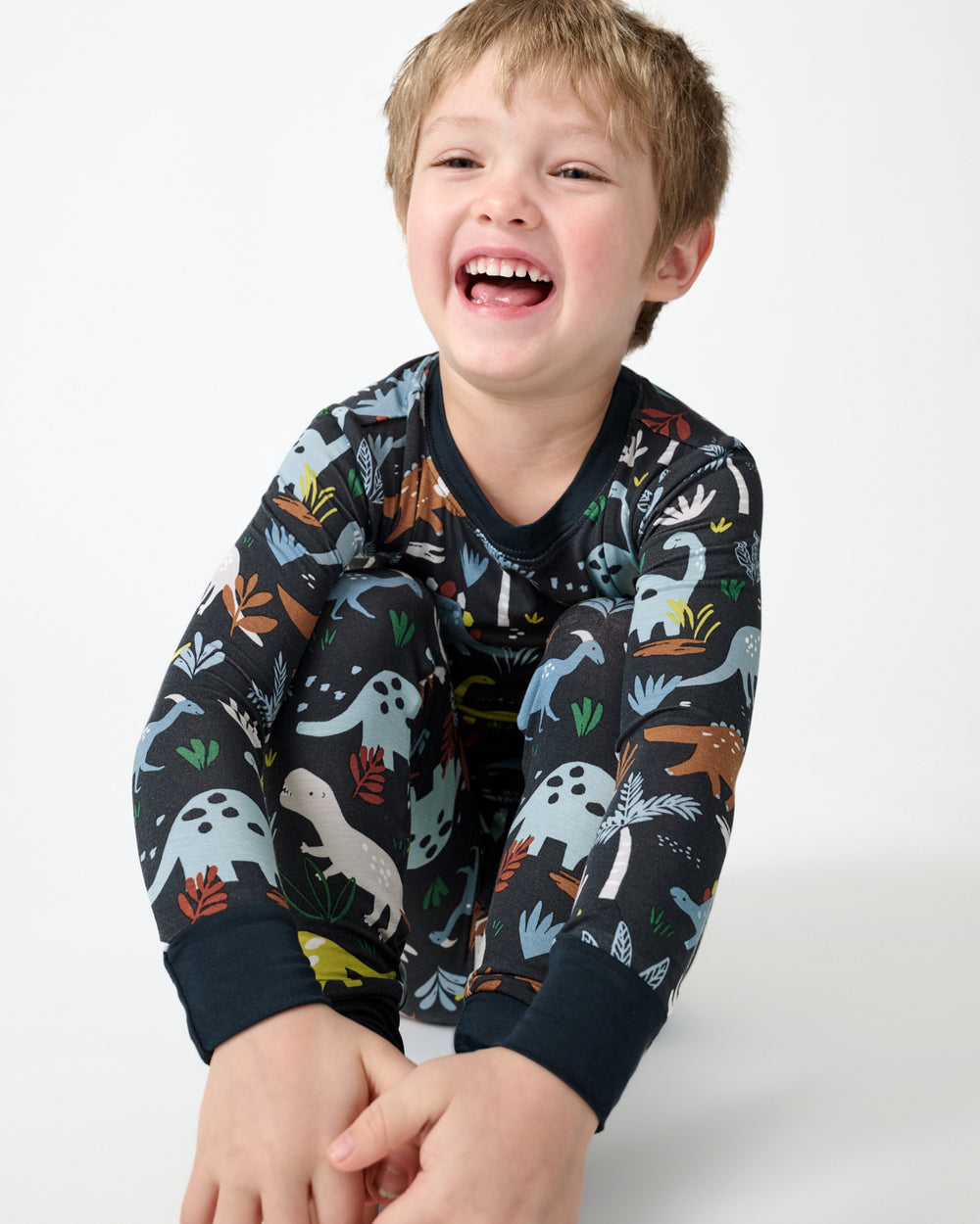 Sitting child wearing the Navy Jurassic Jungle Two-Piece Pajama Set