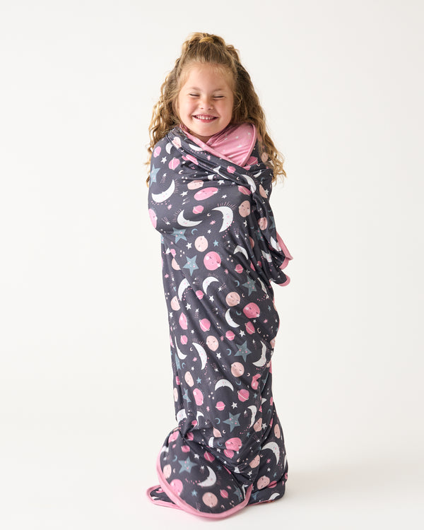 Standing girl wrapped in the Pink To the Moon & Back Large Cloud Blanket®