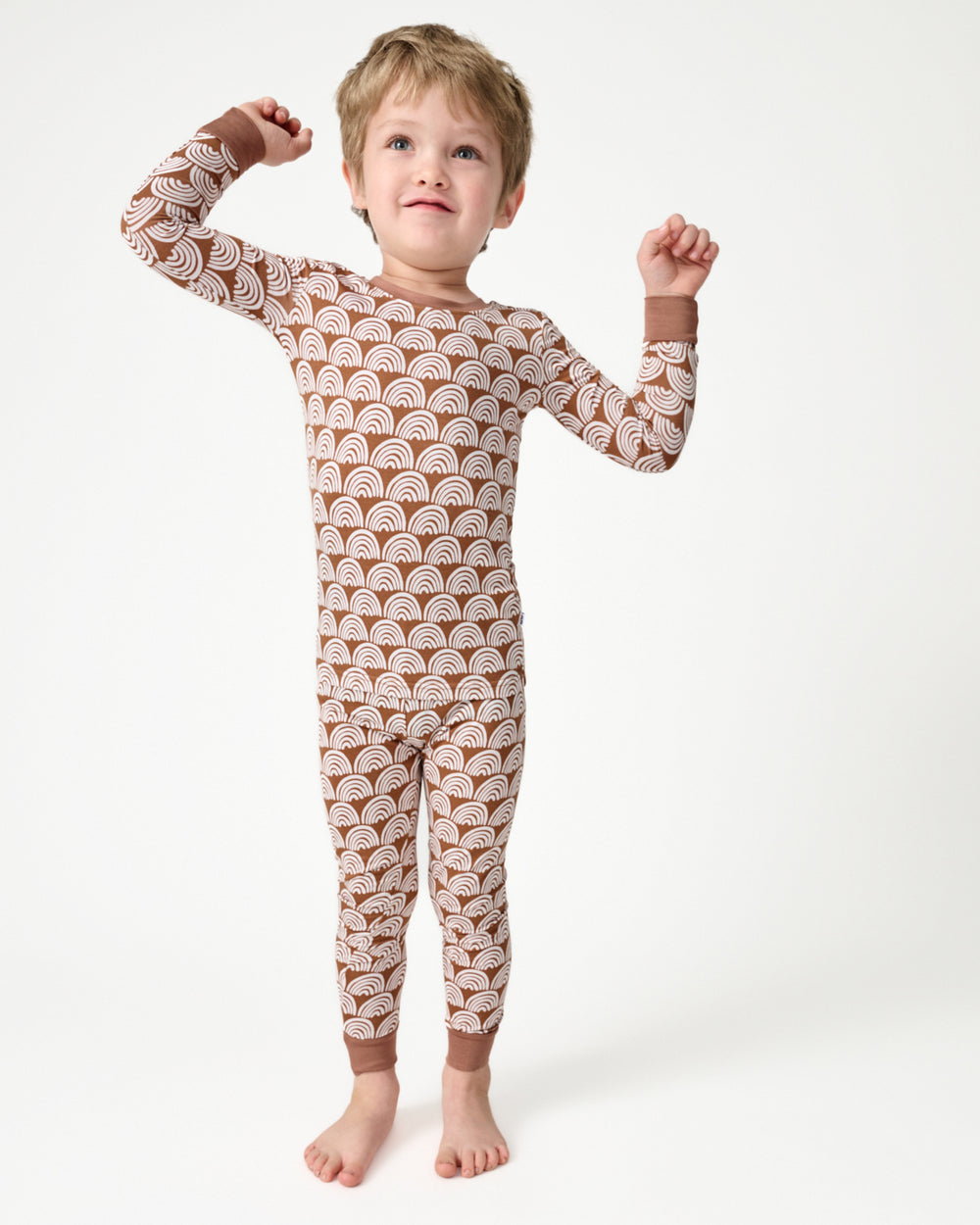 Standing boy wearing the Rust Rainbows Two-Piece Pajama Set