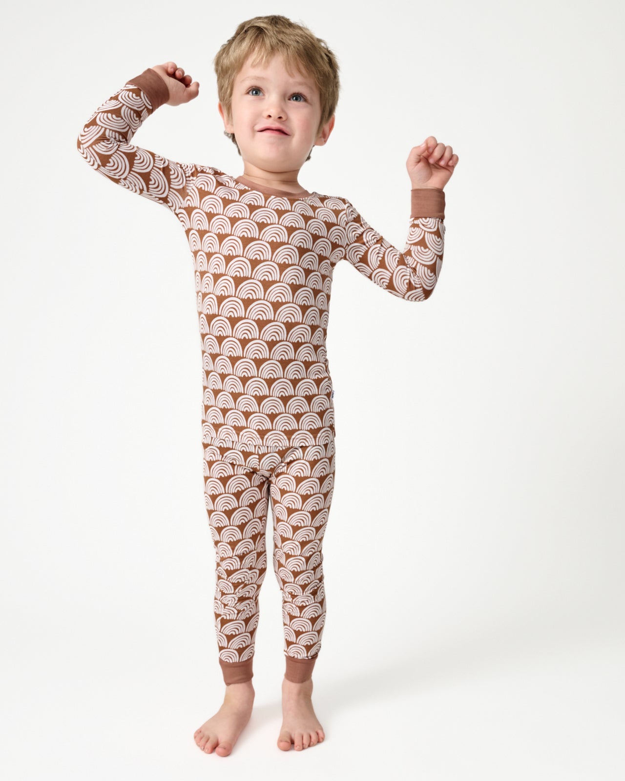 Standing boy wearing the Rust Rainbows Two-Piece Pajama Set