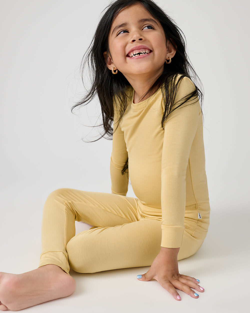 Sitting girl wearing the Sunglow Two-Piece Pajama Set