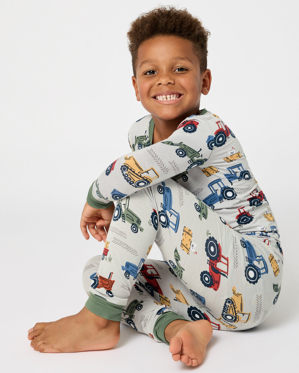 Sitting boy wearing the Tractor Tales Two-Piece Pajama Set