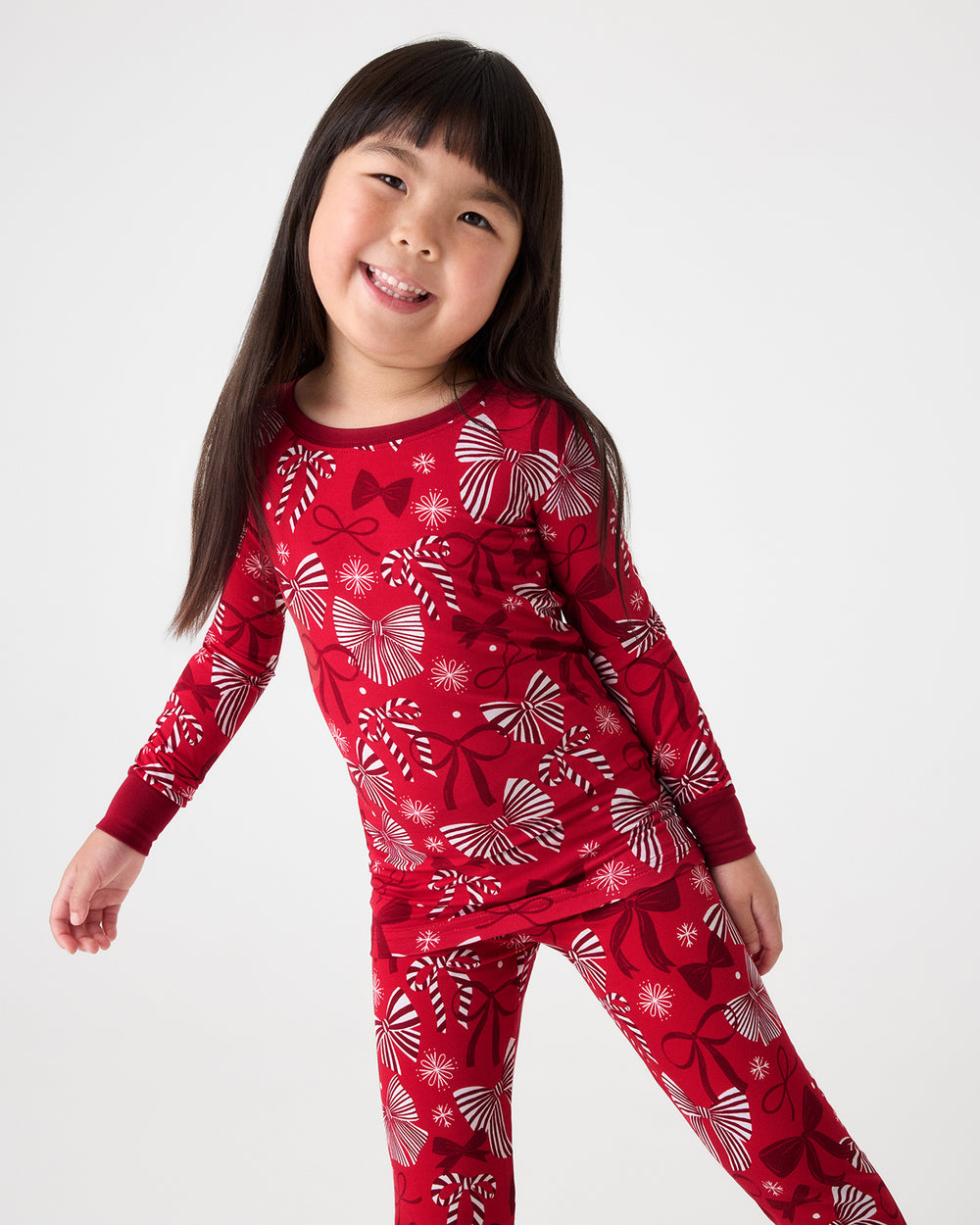 Girl wearing the Holiday Bows Two-Piece Pajama Set featuring red and white ribbons