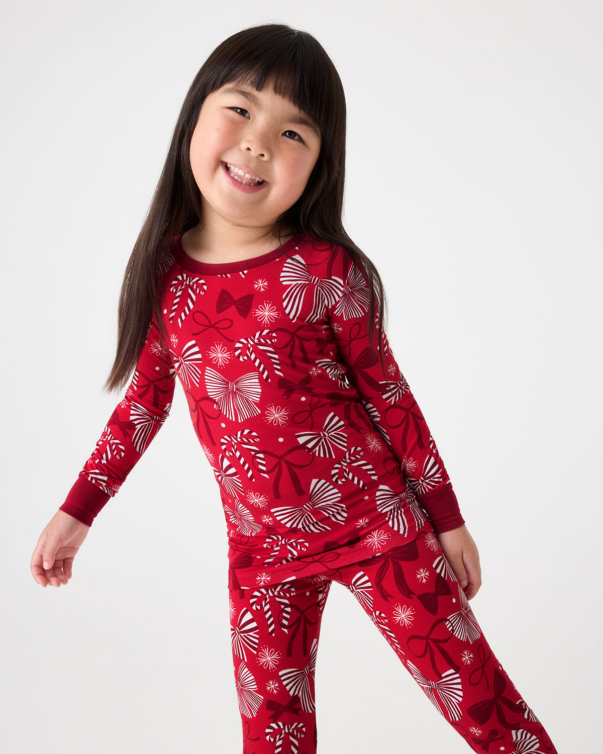 Girl wearing the Holiday Bows Two-Piece Pajama Set featuring red and white ribbons