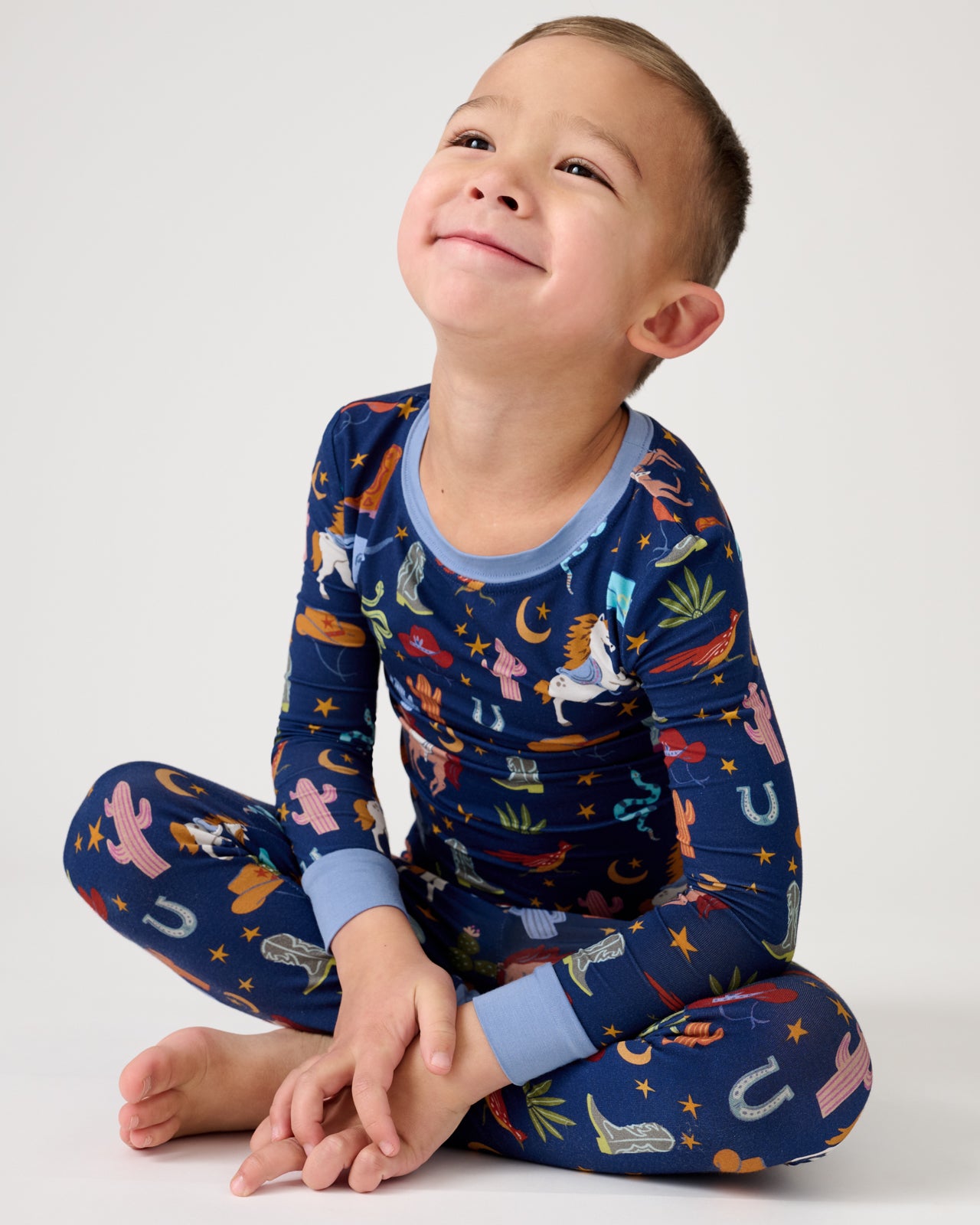 Sitting boy wearing the Blue Rancher Roundup Two-Piece Pajama Set
