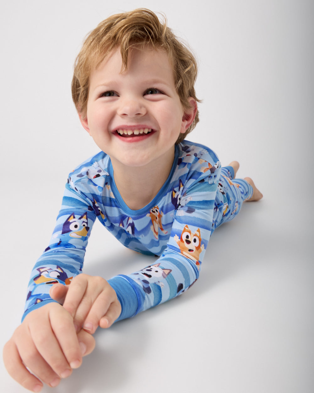 Boy laying on a white surface in the Bluey Dance All Day Two-Piece Bamboo Pajama Set
