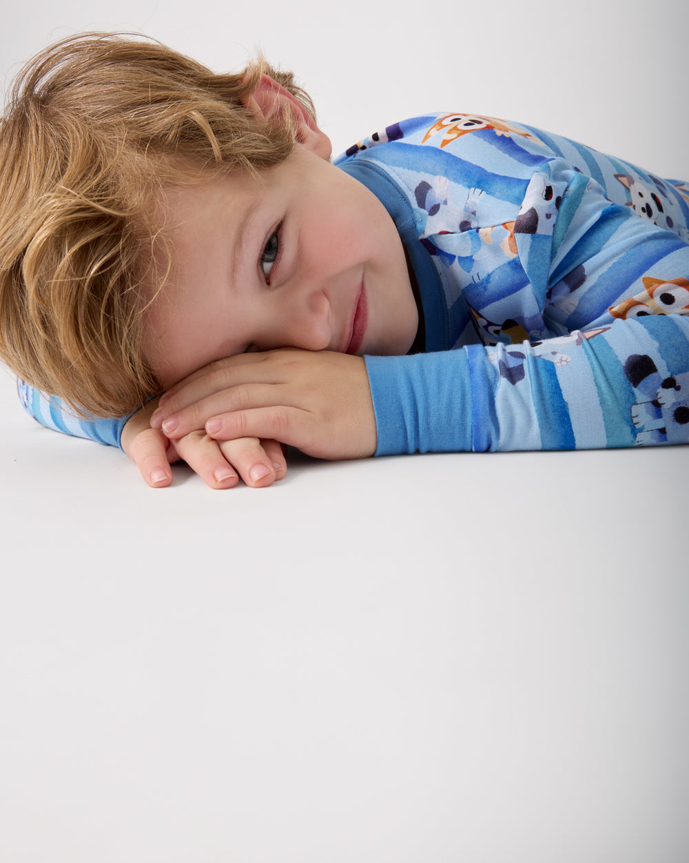 Child laying on a white surface wearing the Bluey Dance All Day Two-Piece Pajama Set
