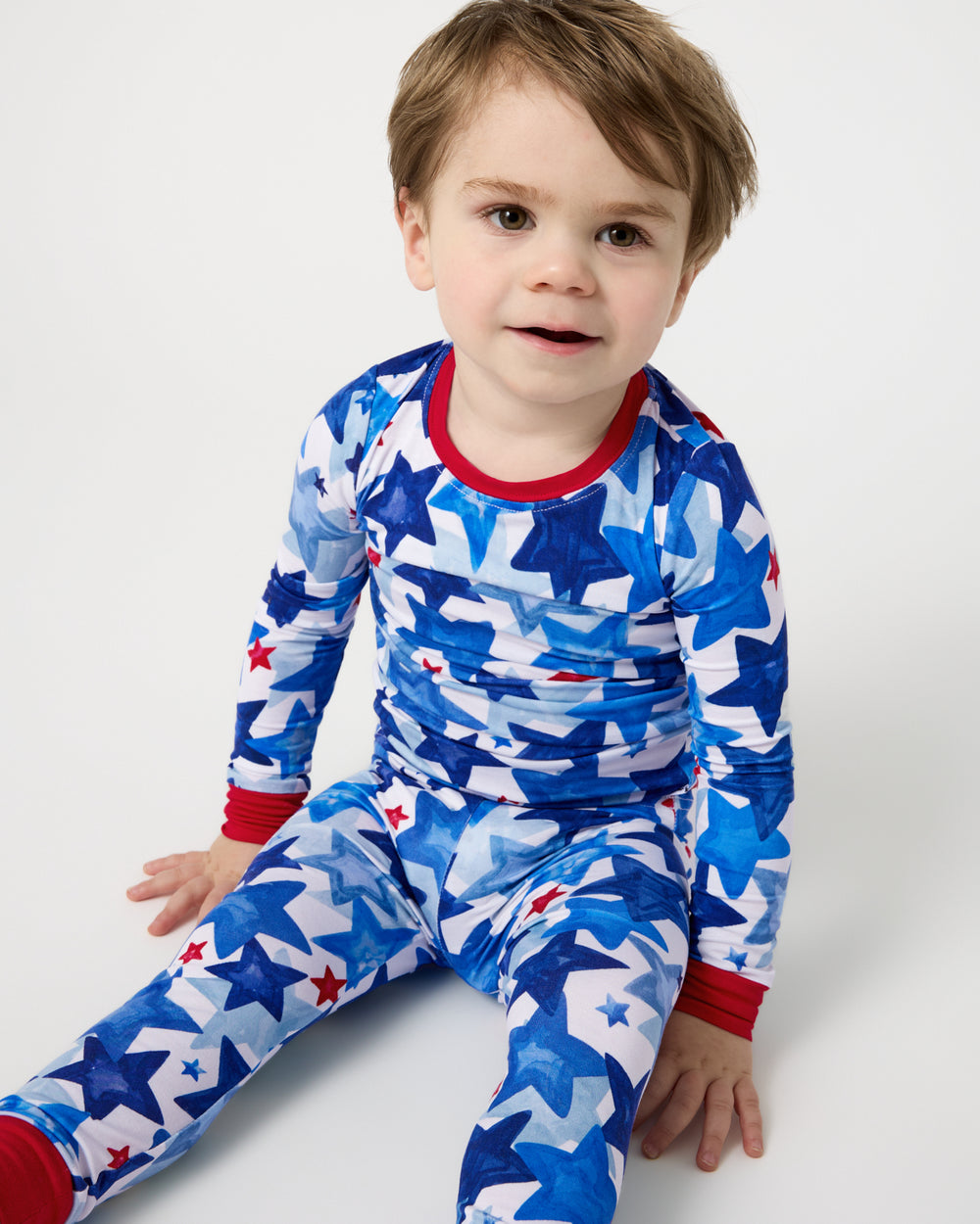 Sitting boy wearing the Starry Splash Two-Piece Pajama Set