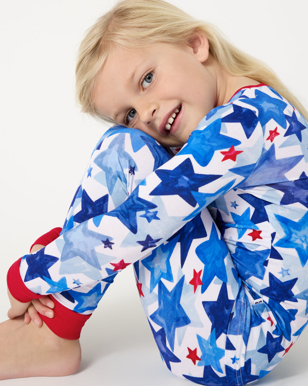 Sitting girl wearing the Starry Splash Two-Piece Pajama Set