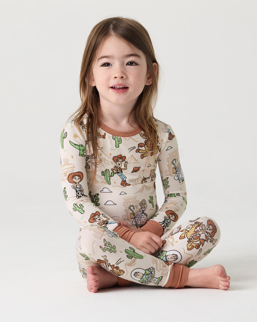 Sitting girl wearing the Disney & Pixar Woody's Wild West Two-Piece Pajama Set