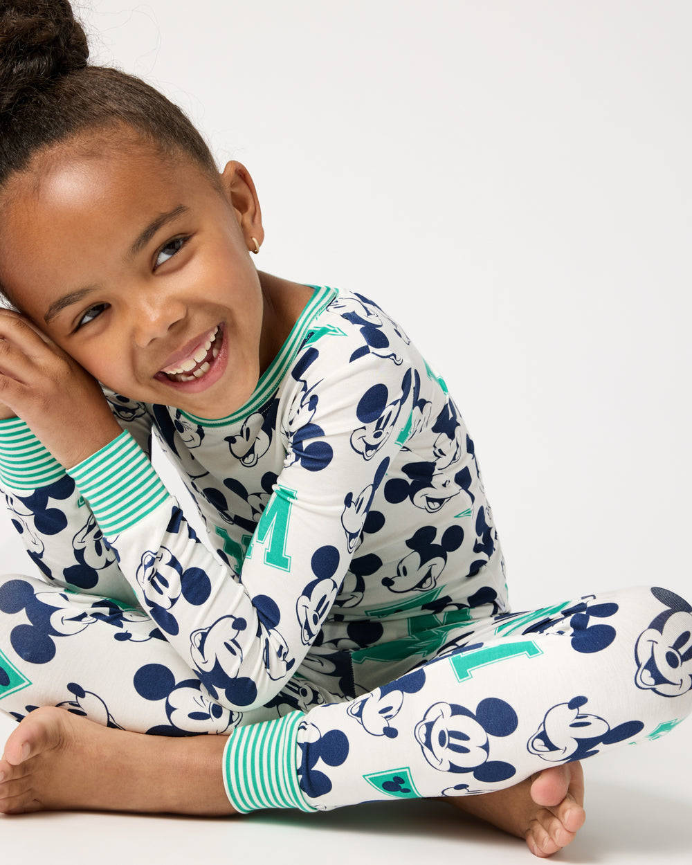 Sitting girl wearing the Disney Varsity Mickey Mouse Two-Piece Pajama Set